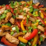 Fried chicken with colorful bell peppers, onions, and green onions, cooked to perfection for a quick and healthy meal.